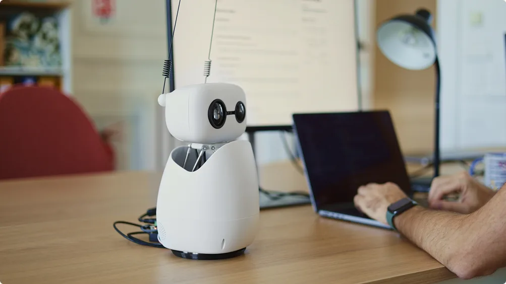 Reachy Mini sur un bureau, à côté d'un ordinateur portable
